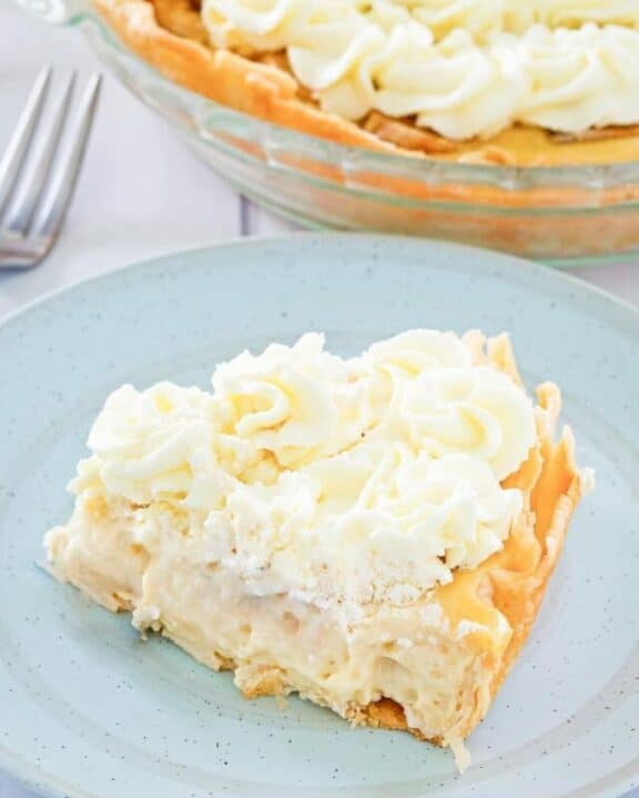 a slice of banana cream pie on a plate with the pie behind it