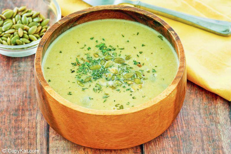 a bowl of acorn squash soup topped with cilantro and pumpkin seeds.
