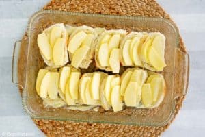 assembling apple bread pudding in a baking dish.