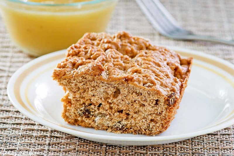 applesauce cake slice on a plate and a small bowl of applesauce.