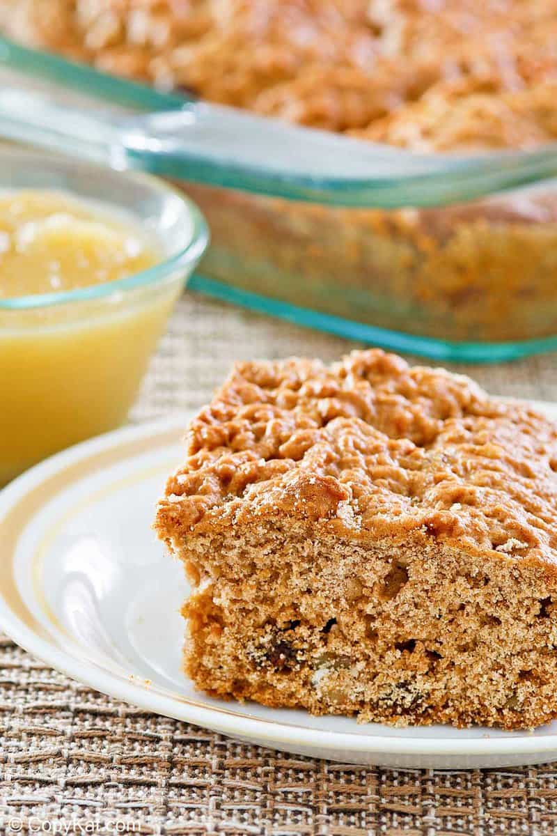a slice of applesauce cake on a plate and applesauce in a small bowl.