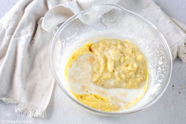 adding mashed bananas to cake batter in a mixing bowl.