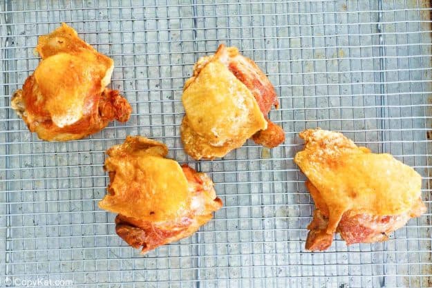 deep fried chicken thighs on a wire rack.