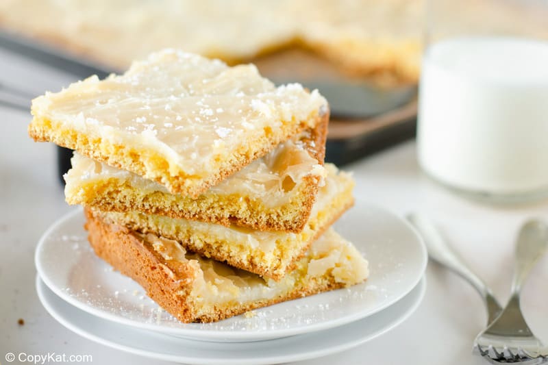 four gooey butter cake slices on a plate and a glass of milk.