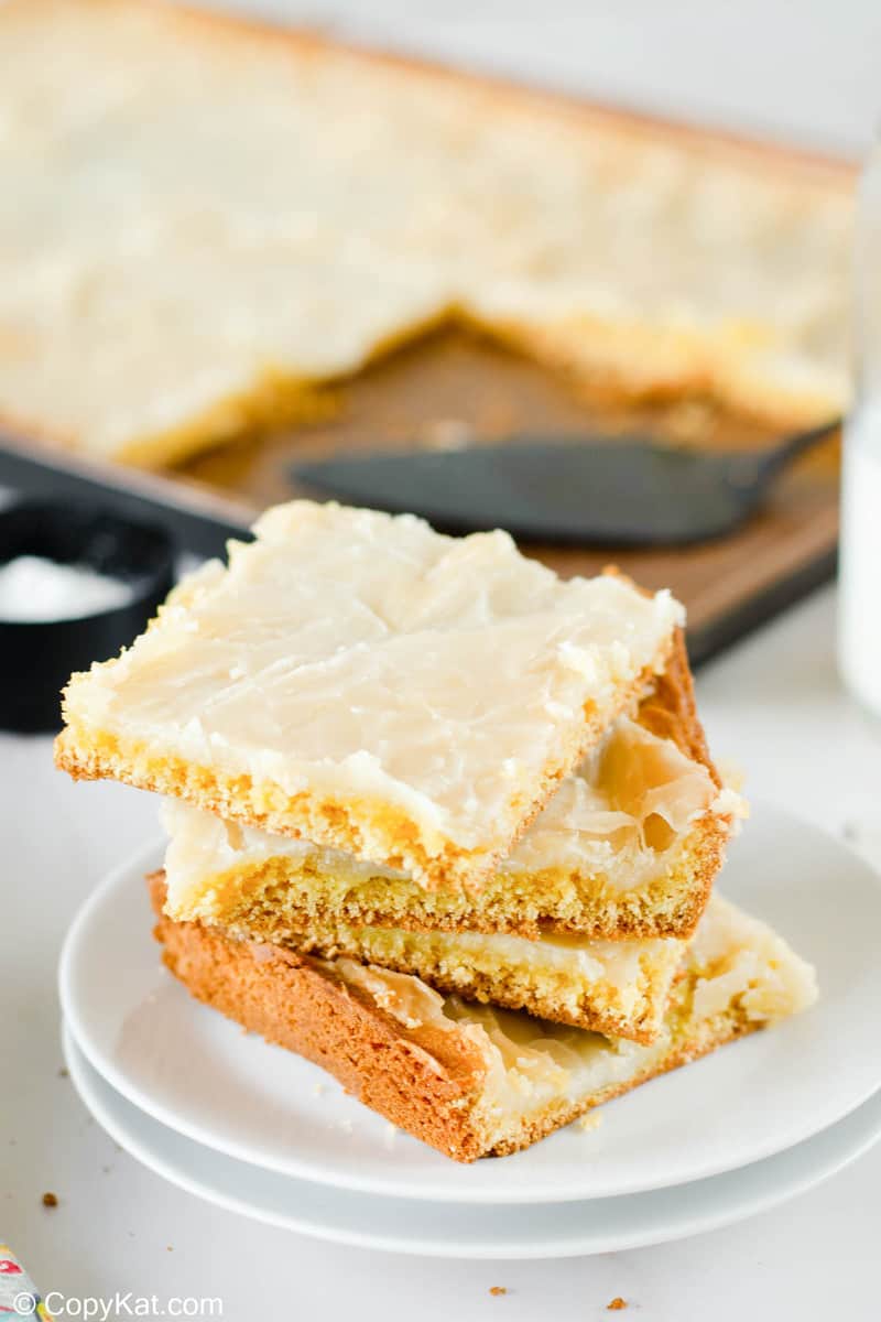 four gooey butter cake slices on a plate in front of the cake in a pan.