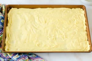 gooey butter cake batter spread out in a jelly roll pan.