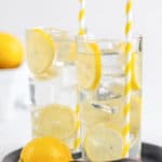two glasses of homemade lemonade and a lemon on a tray.