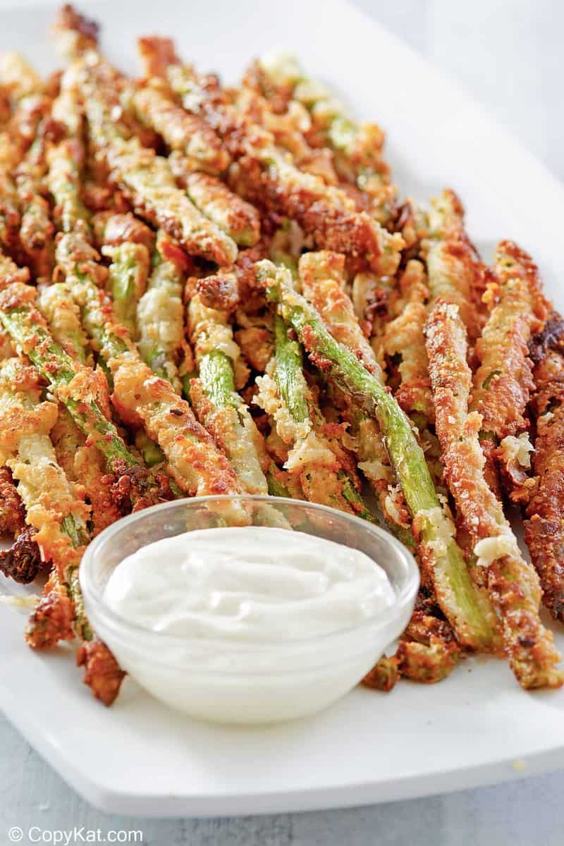 homemade Longhorn parmesan crusted asparagus and ranch sauce on a platter.