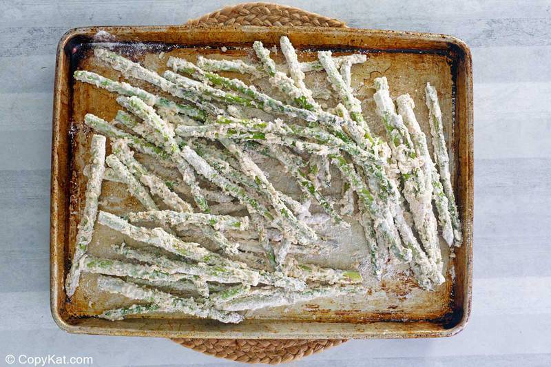 parmesan and flour coated asparagus on a baking sheet.