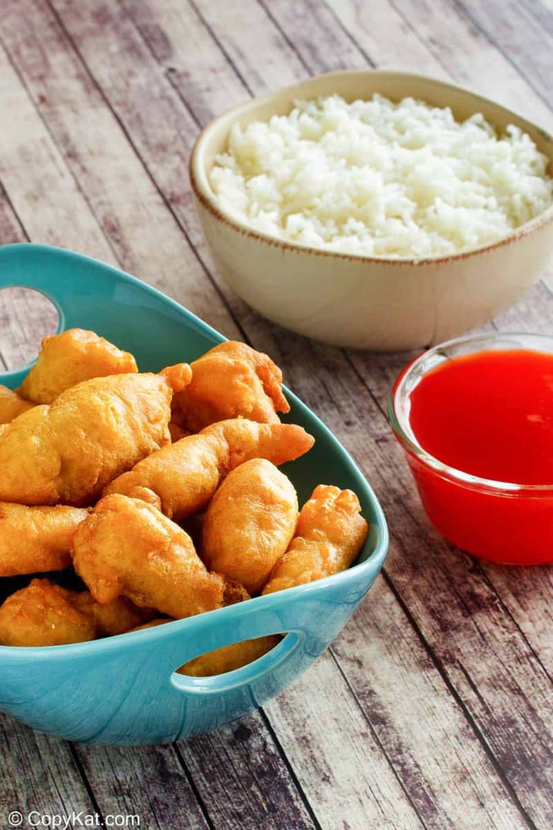sweet and sour chicken, sauce, and a bowl of rice.