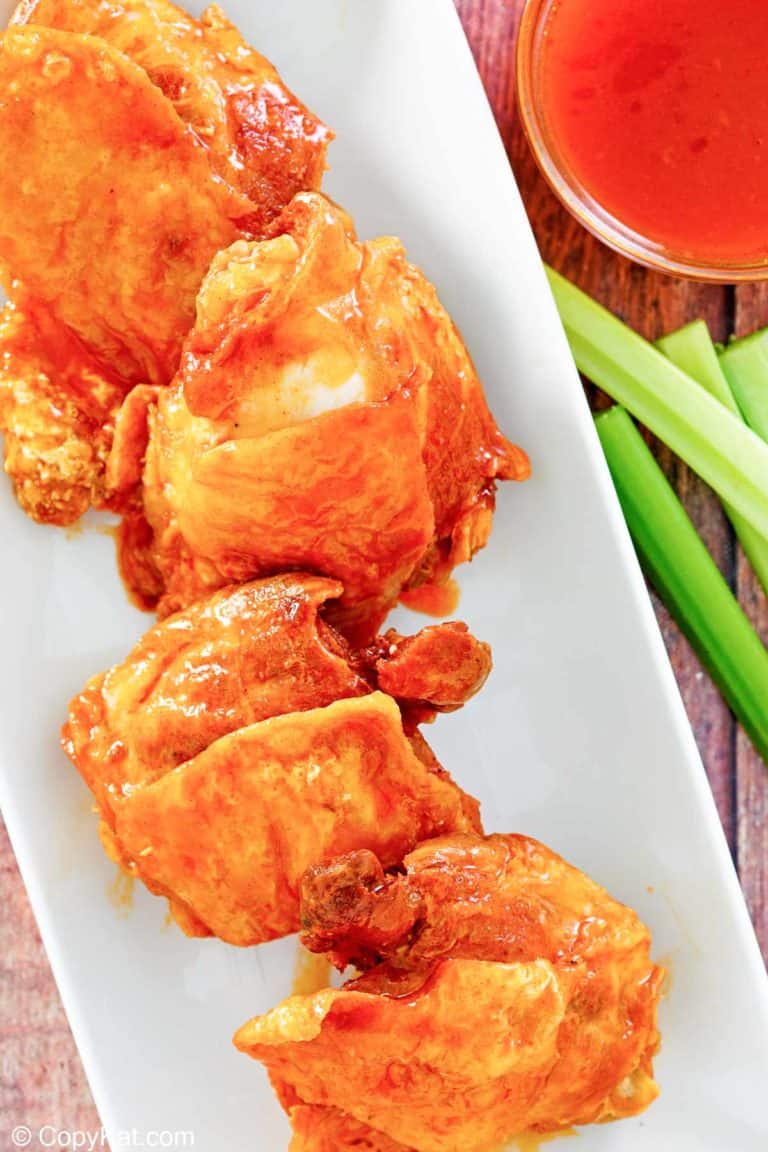 four homemade Wingstop Buffalo chicken thighs, Buffalo sauce, and celery sticks.
