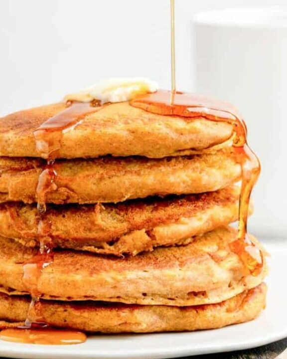 a stack of homemade IHOP pumpkin pancakes with syrup flowing over them.