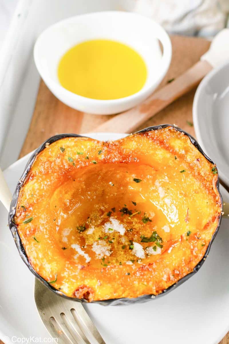 air fryer acorn squash on a plate and a bowl of melted butter.