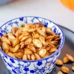 air fryer pumpkin seeds in a blue bowl on top of a black plate.