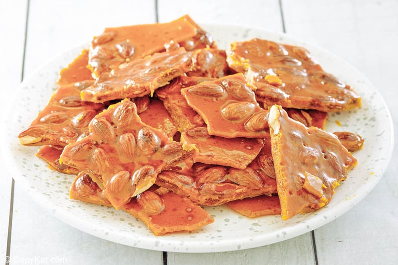 homemade almond brittle candy on a white plate.