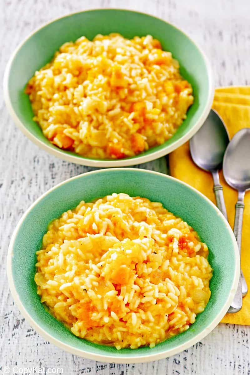 two bowls of butternut squash risotto and two spoons.