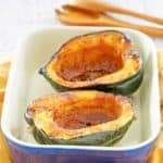 microwave acorn squash with brown sugar butter sauce in a serving dish.