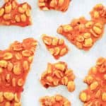 overhead view of microwave peanut brittle pieces on parchment paper.