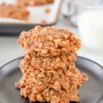 four no bake chocolate oatmeal cookies stacked on a plate.