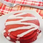 red velvet pancakes with cream cheese glaze, fork, and napkin.