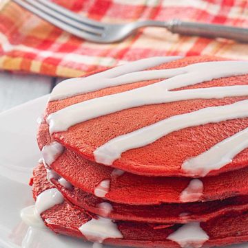 red velvet pancakes with cream cheese glaze on a plate.