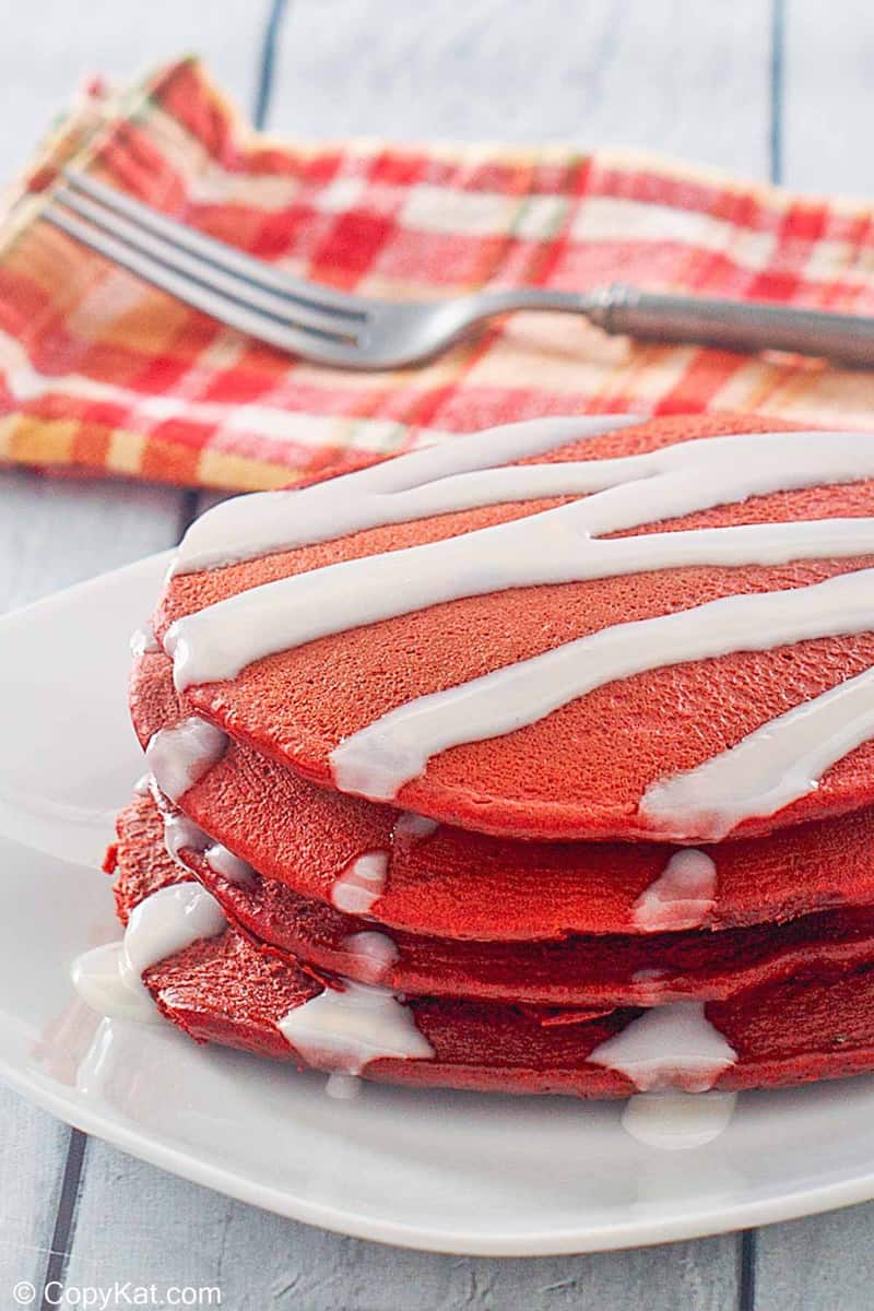 red velvet pancakes with cream cheese glaze on a plate.
