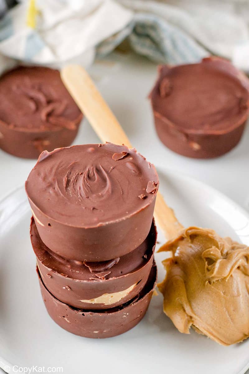five homemade Reese's peanut butter cups and peanut butter on a wooden spoon.