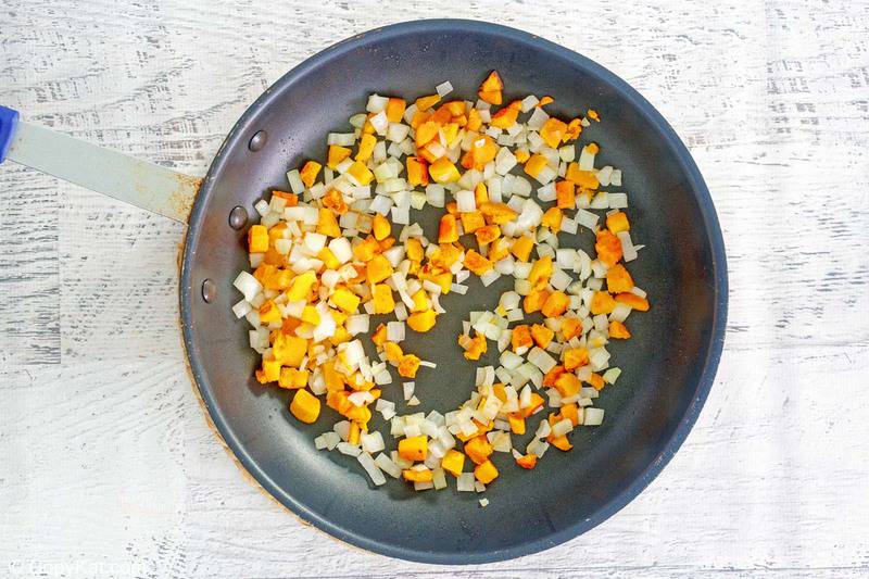 sauteed diced butternut squash and onions in a skillet.