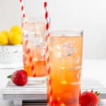 homemade Sonic Strawberry Lemonade in two glasses, fresh strawberries and lemons.