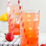 two glasses of homemade Sonic strawberry lemonade, fresh strawberries and lemons.