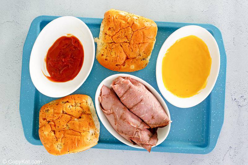 Arby's beef and cheddar sandwich ingredients on a tray.