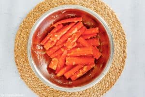 a bowl of carrots coated in a honey mixture.