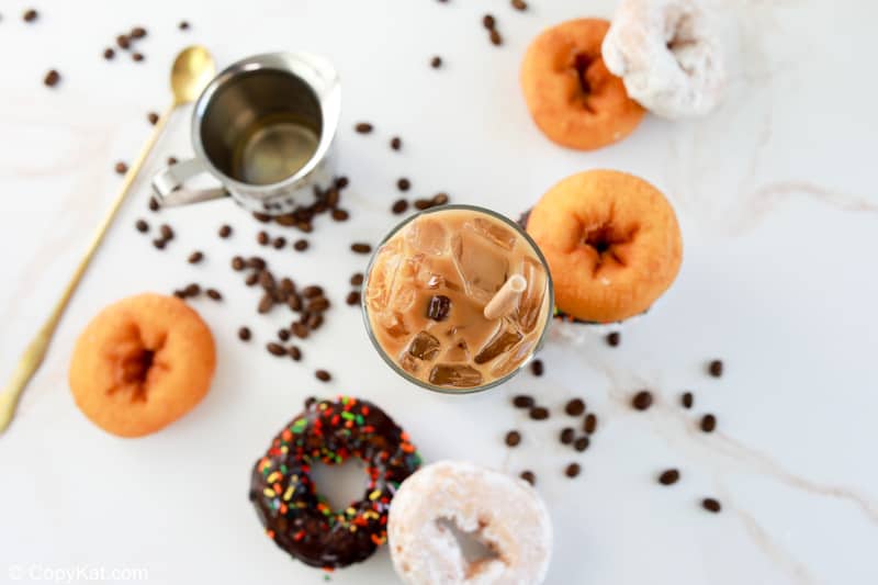 overhead view of homemade Dunkin Donuts iced coffee, coffee beans, and donuts.