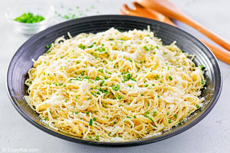 bowl of garlic butter pasta topped with chives and cheese.