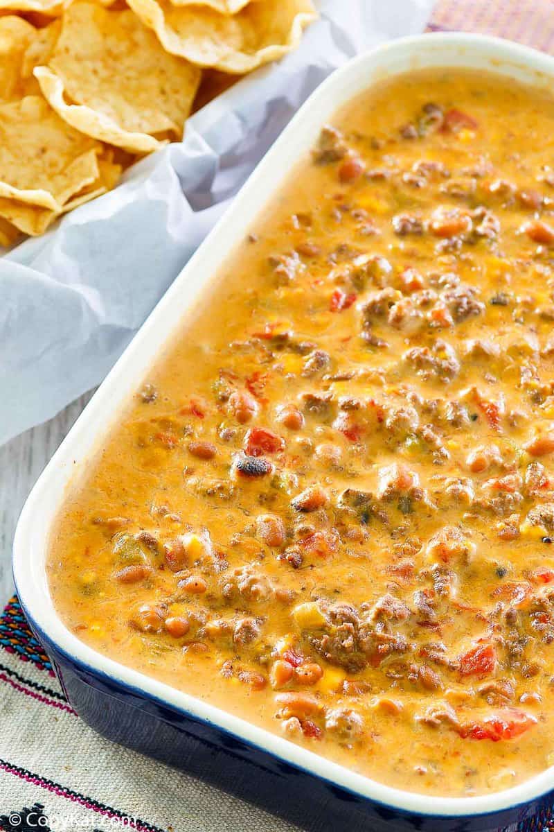 hamburger dip next to a basket of tortilla chips.