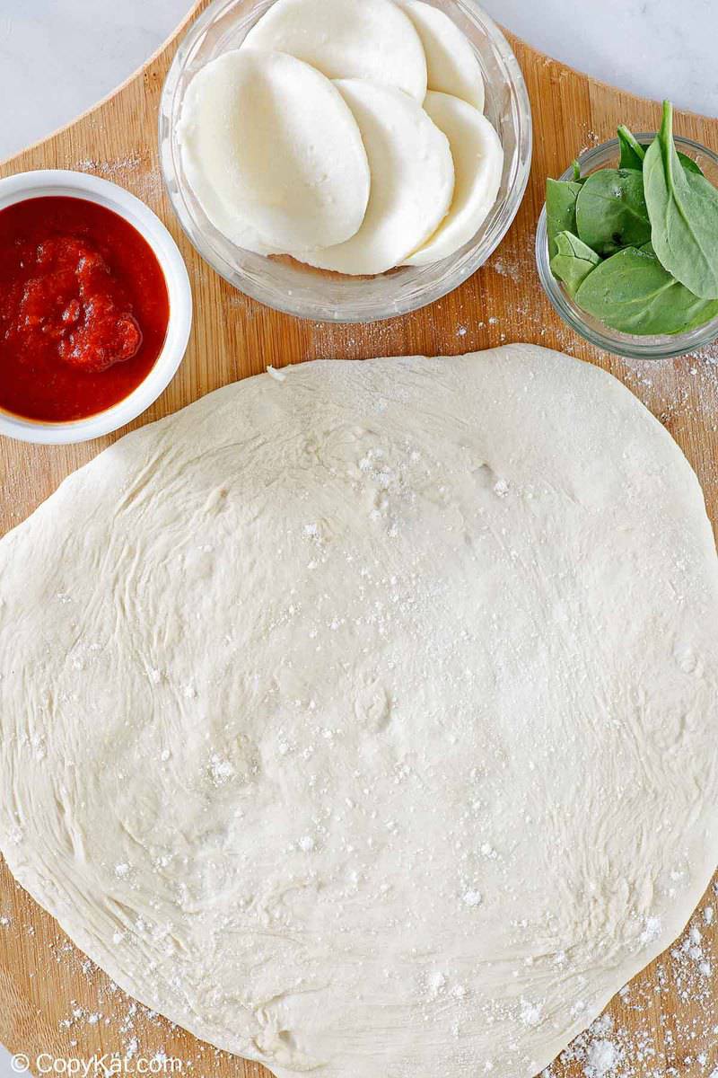 overhead view of homemade pizza dough rolled out on a pizza peel.