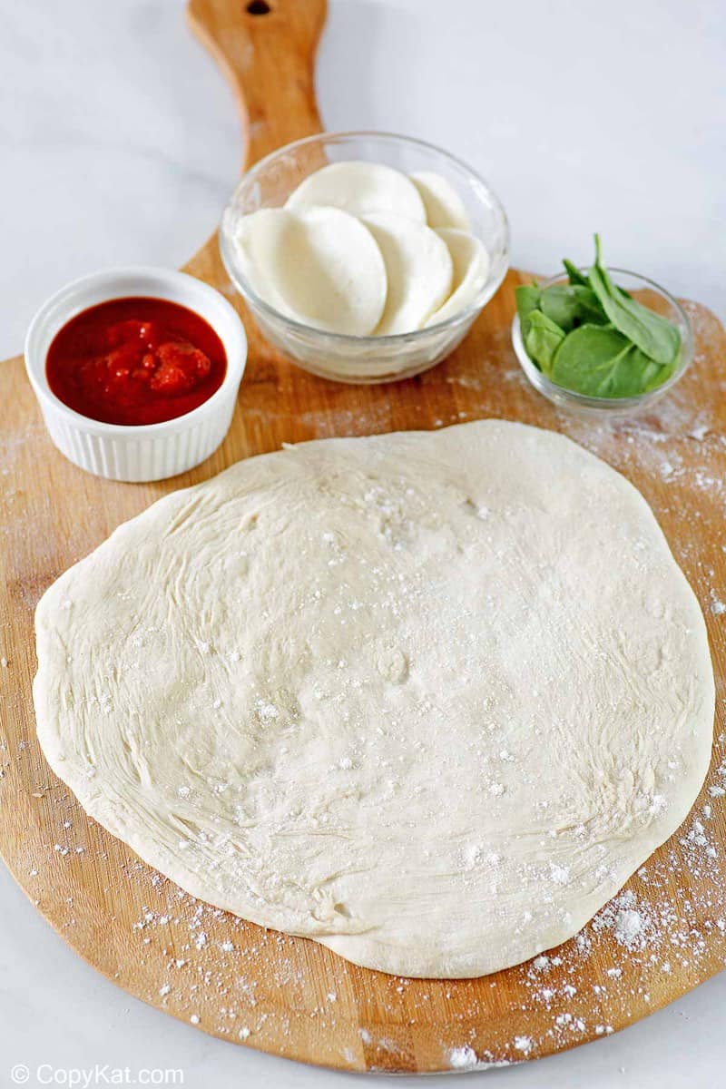 homemade pizza dough rolled out on a pizza peel.