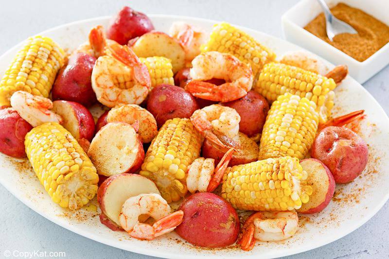 shrimp boil on a platter and homemade old bay seasoning in a small dish.