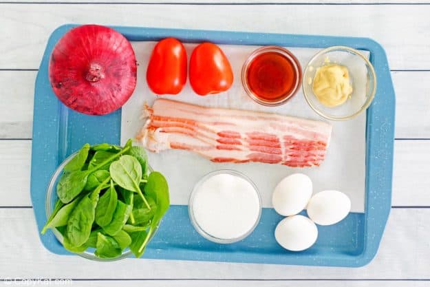spinach salad with hot bacon dressing ingredients on a tray.