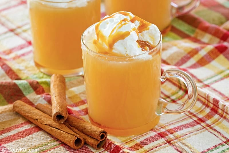 homemade Starbucks caramel apple spice drink in a mug and cinnamon sticks.