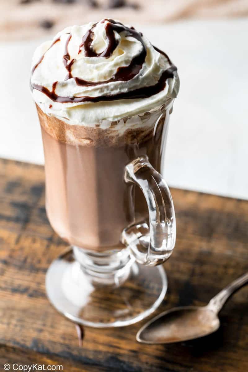 homemade Starbucks hot chocolate in a glass mug on a wood board.