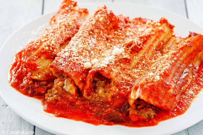 meat and cheese stuffed manicotti with sauce on a plate.