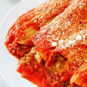 meat and cheese stuffed manicotti with sauce and romano cheese.