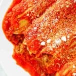 closeup of meat and cheese stuffed manicotti with sauce.