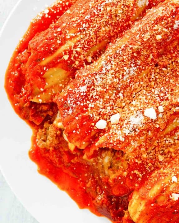 closeup of meat and cheese stuffed manicotti with sauce.