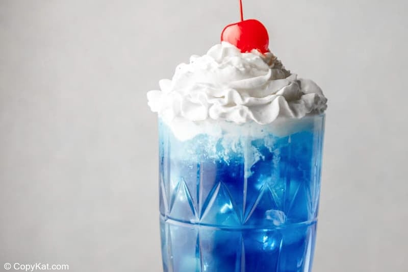 homemade Ruby Tuesday Blue Smurf Punch Drink with whipped cream and a cherry.
