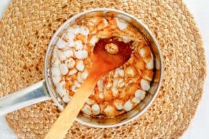 adding marshmallows to boiled frosting in a pan.