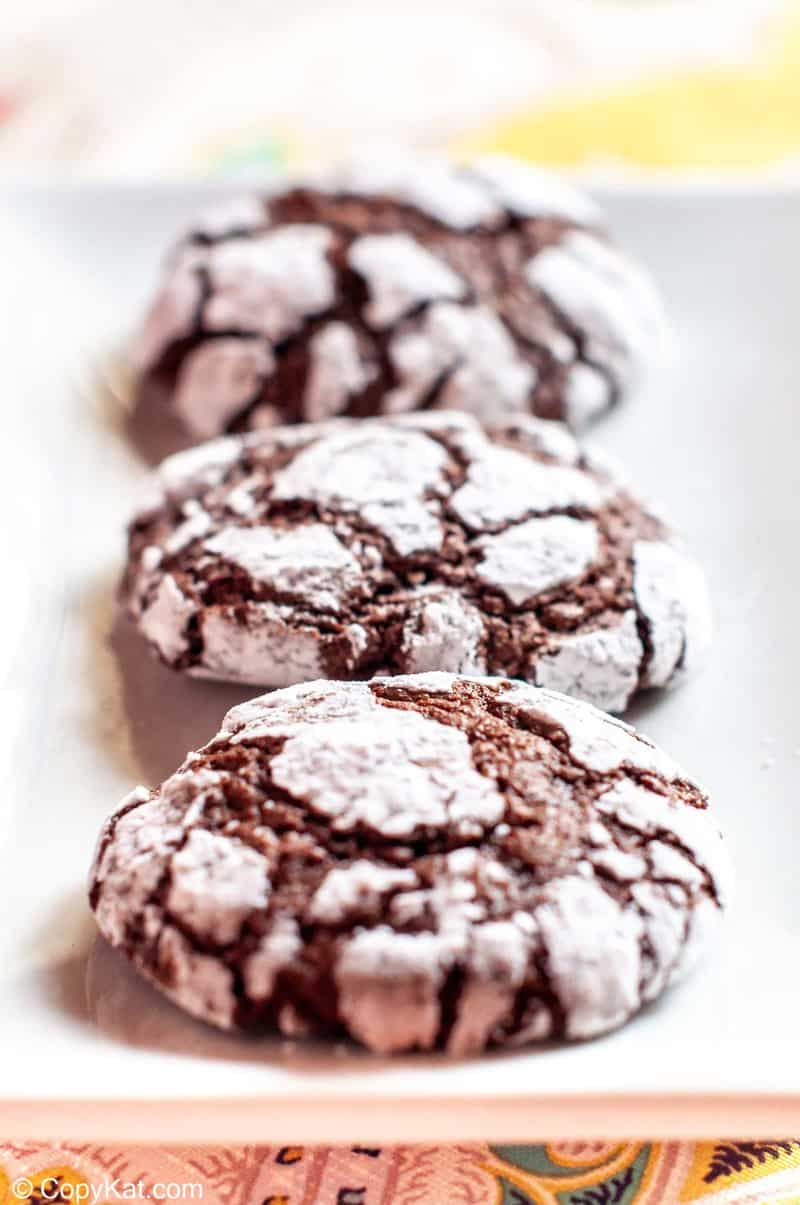 three chocolate crinkle cookies on a plate.