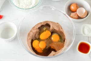 adding eggs to cocoa mixture for chocolate crinkle cookies.
