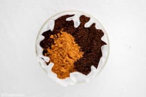 coffee grounds and ground cinnamon in a coffee filter.